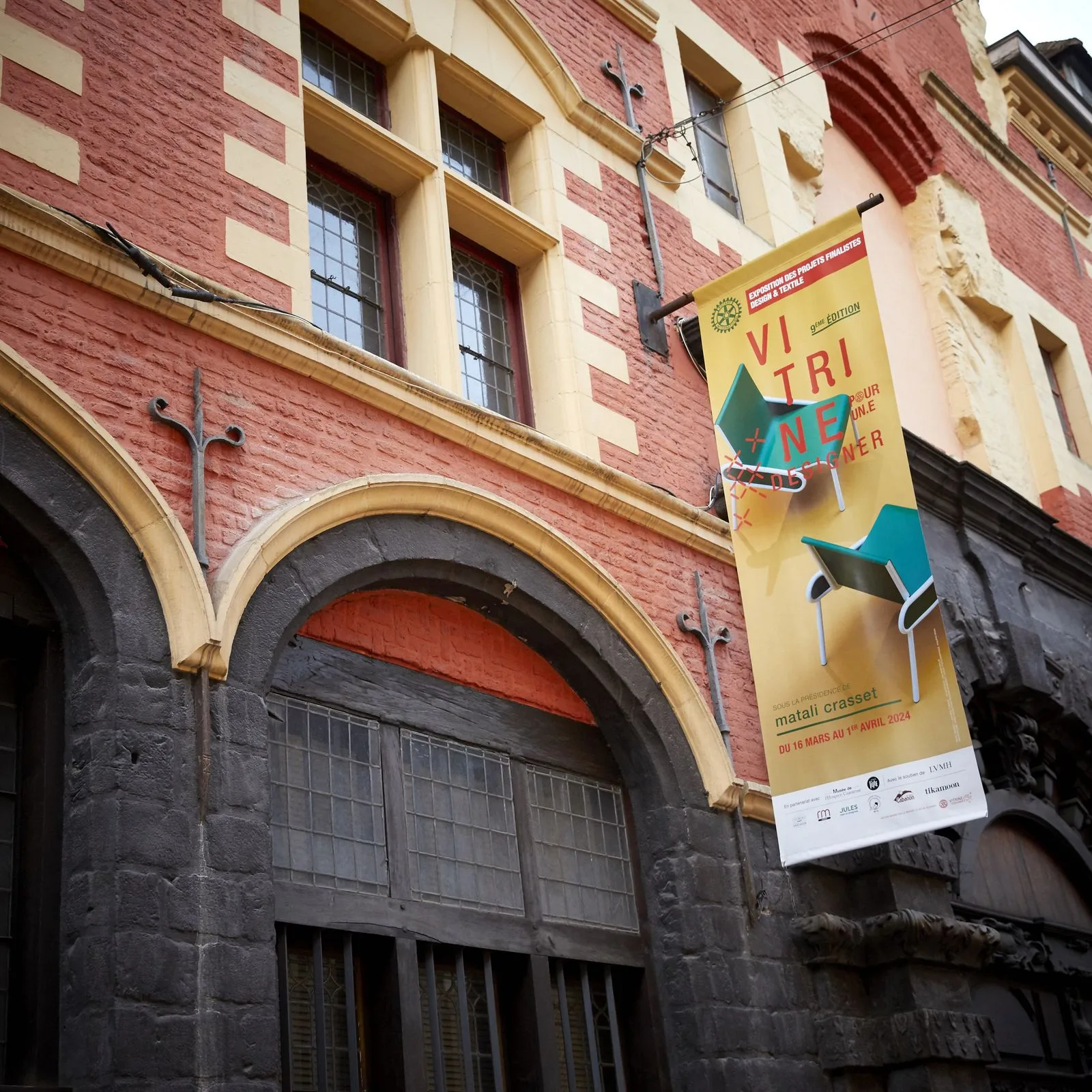 Le calicot de Vitrine pour un.e Designer déployé sur la façade du musée de l'Hospice Comtesse, rue de la Monnaie à Lille.