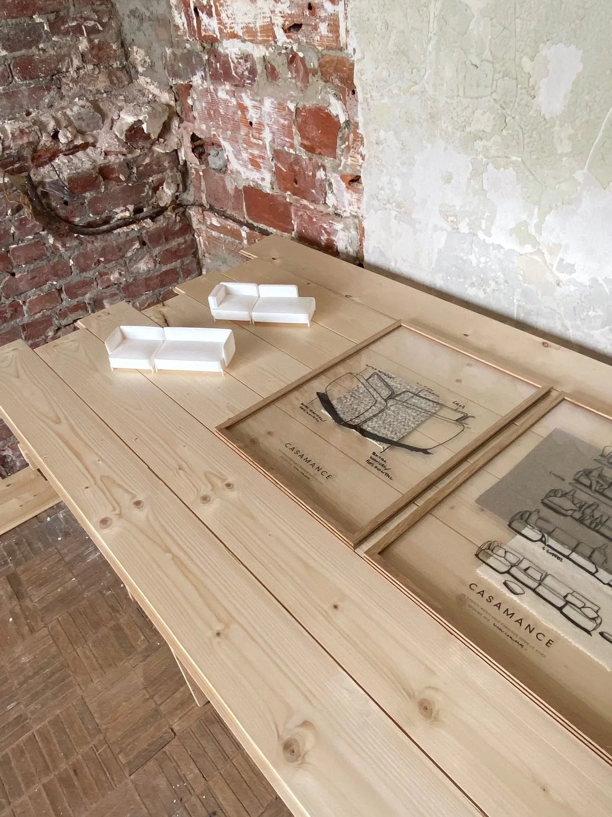Plans et maquettes du canapé CONTOUR posés sur un plan de travail en bois.