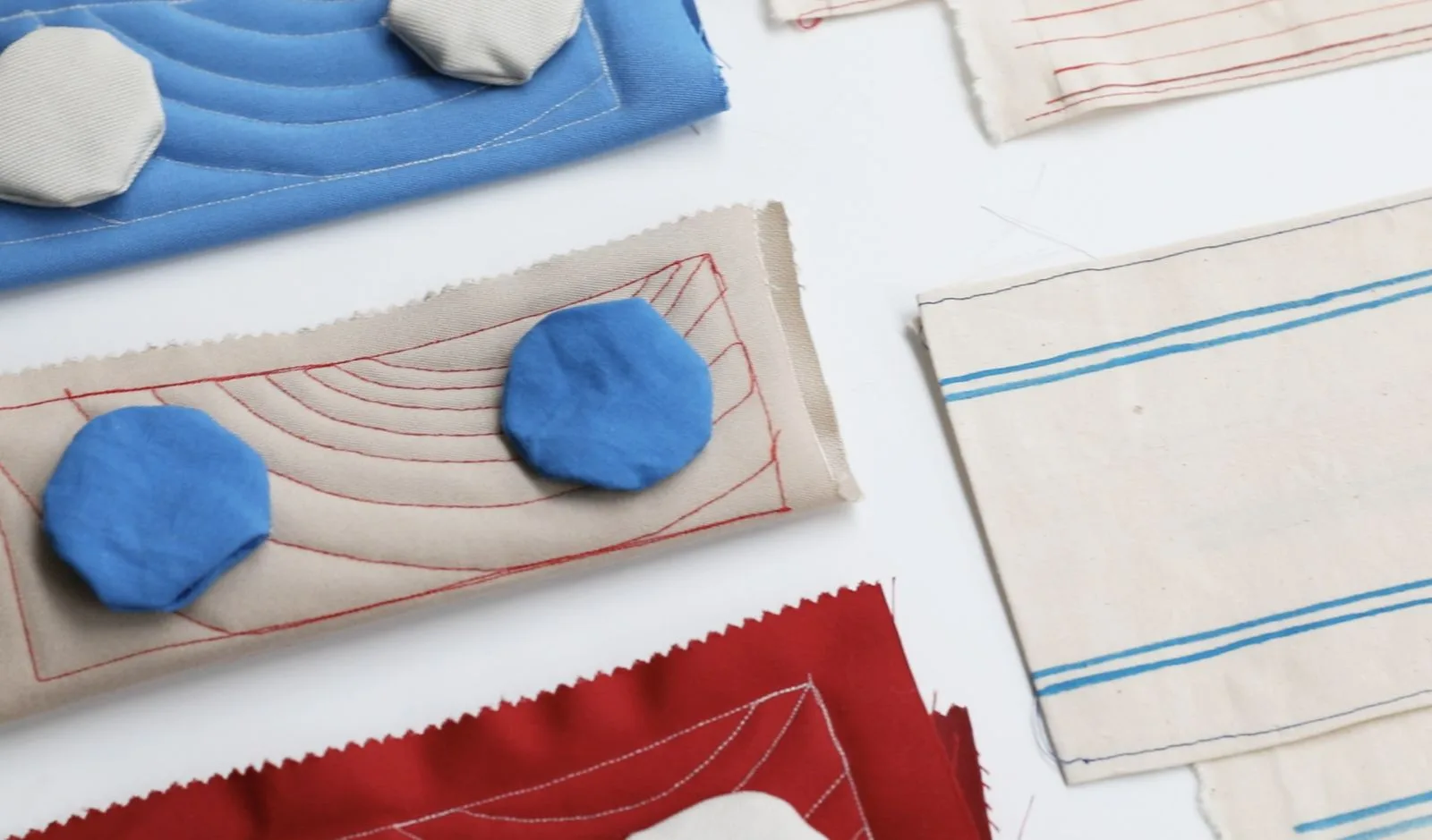 Échantillons textiles et formes bleues découpées, disposés sur une table.
