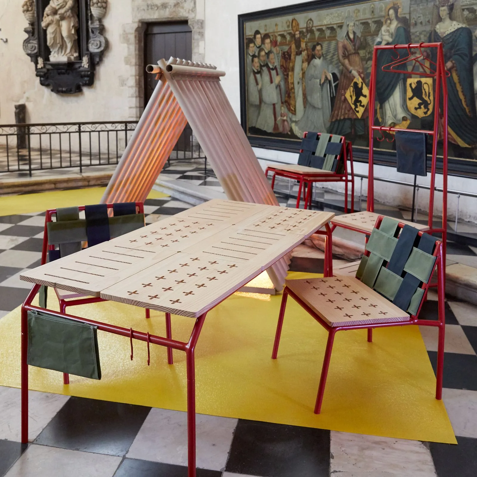 La gamme Ligne dé-tente exposée à l'Hospice Comtesse : table, chaises et portant, sur un tapis jaune posé au sol en damier.
