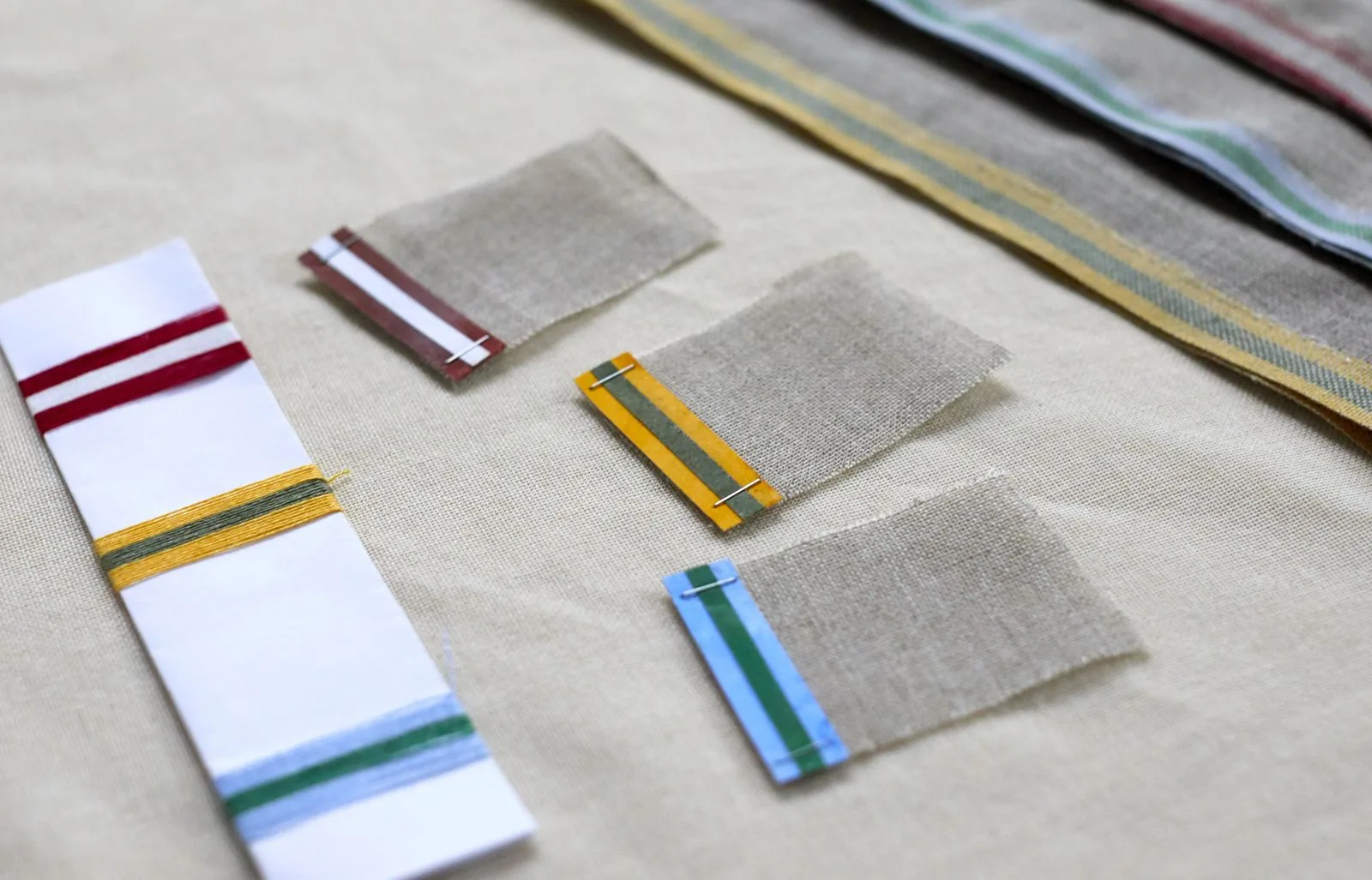 Échantillons de bandes tissées à rayures colorées, disposés à plat sur une table blanche.