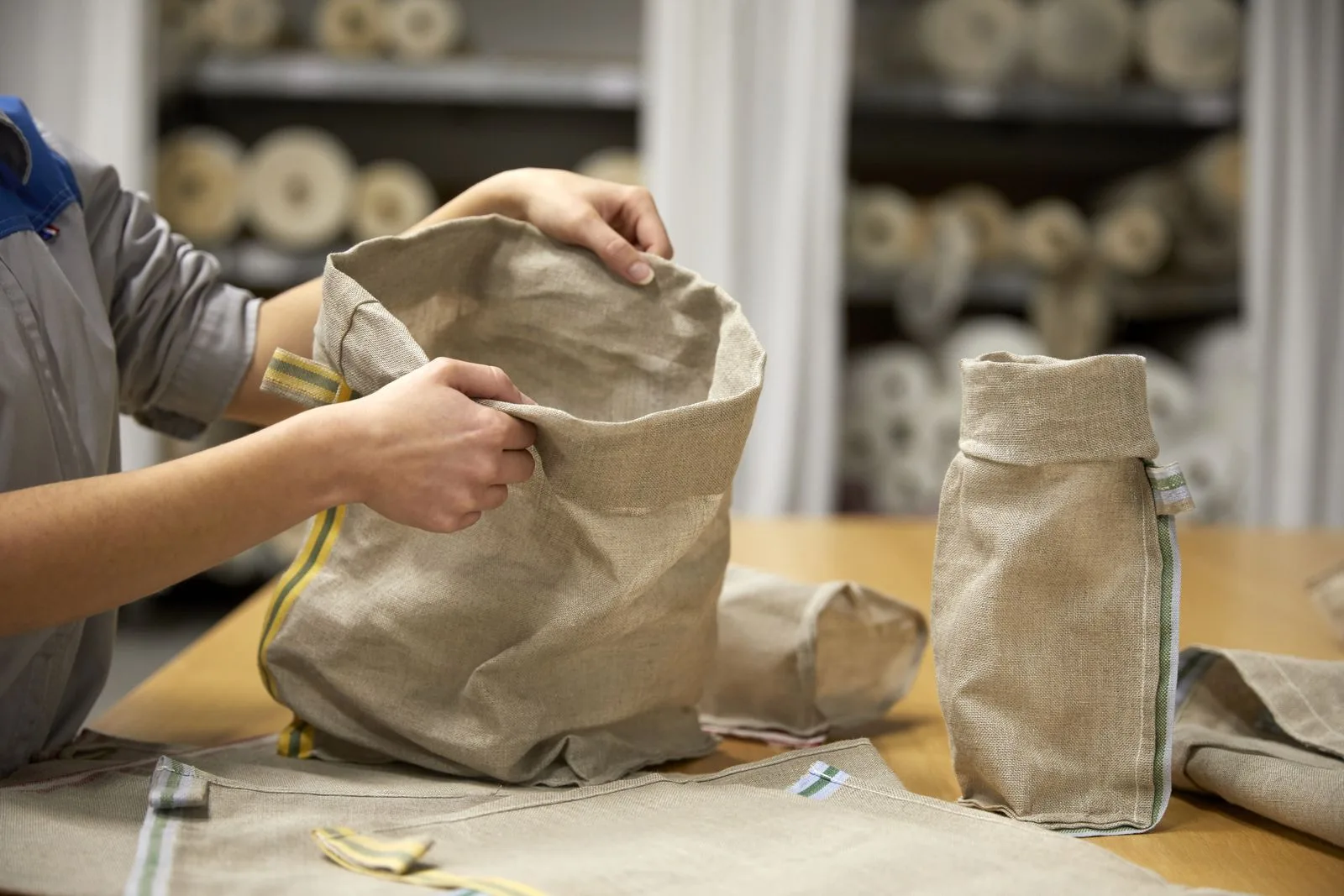 Deux mains ouvrent un sac de lin posé sur un plan de travail.