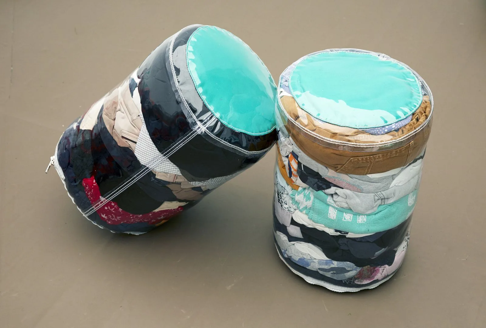 Deux assises cylindriques UNITÉS TEXTILES posées au sol, dessus vert d'eau et flancs de chutes textiles.